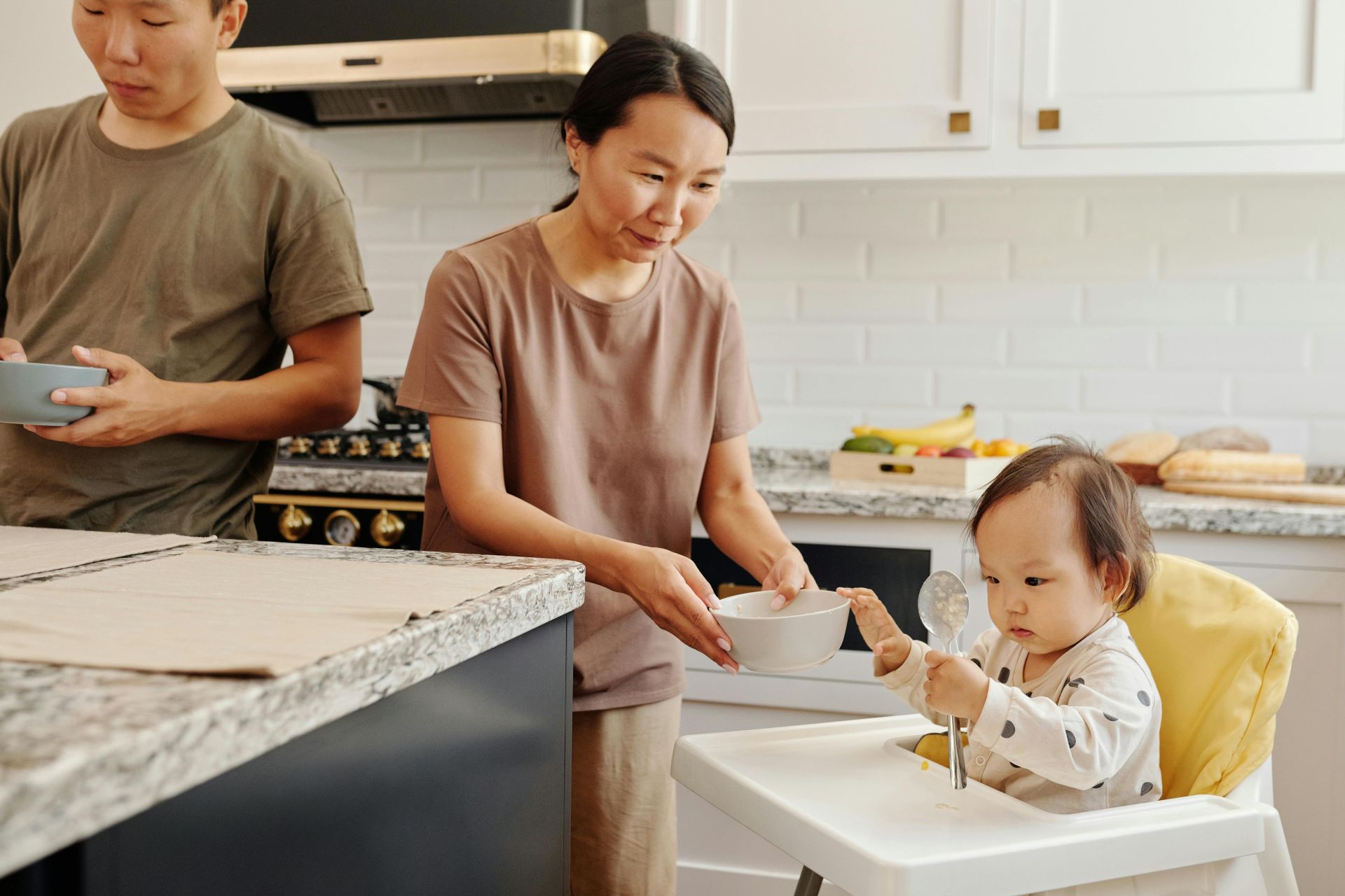 An Asian family with a baby enjoying meal time together in a stylish kitchen.
